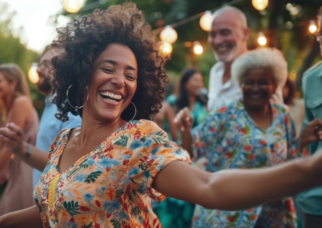 A woman is dancing with a group of people. She is smiling and having a good time. The atmosphere is lively and fun. Diverse Multicultural Friends, Family, Celebration, Housewarming, Summer